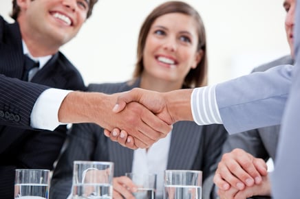 Smiling businessman and his colleague closing a deal with a partner in a meeting